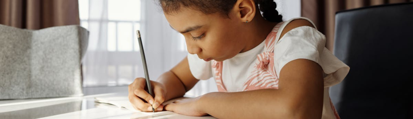 A little girl sitting at a table and doing her homework